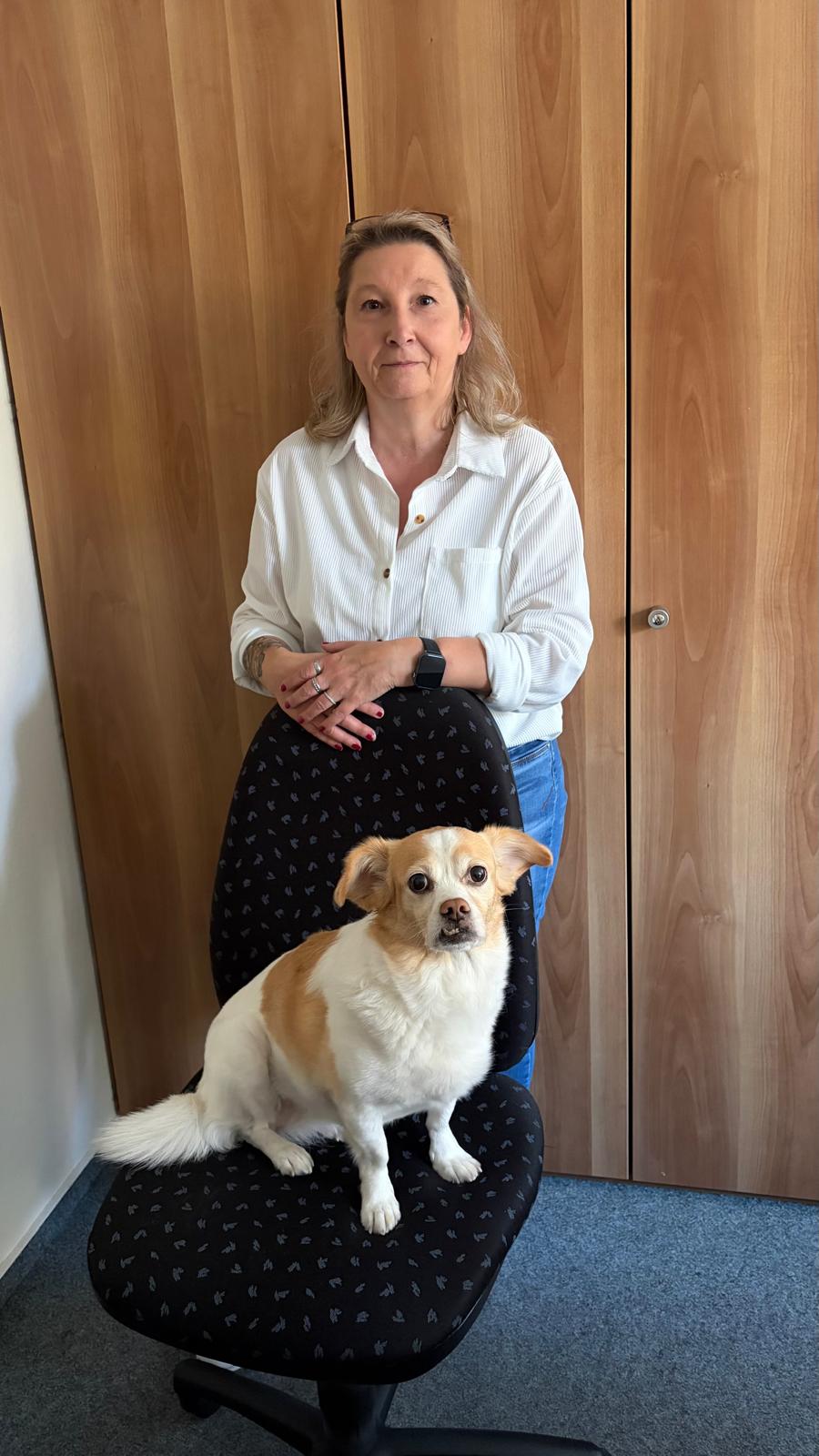 Renate, Mitarbeiterin im Backoffice bei Pudelwohl365, mit ihrer Hündin Nika auf dem Bürostuhl